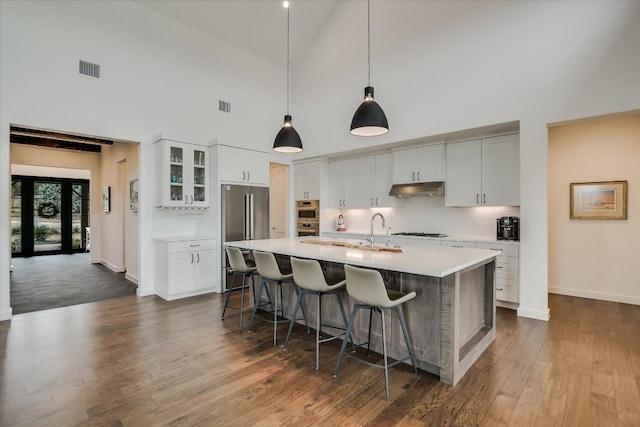 kitchen with a breakfast bar area, light countertops, visible vents, appliances with stainless steel finishes, and under cabinet range hood