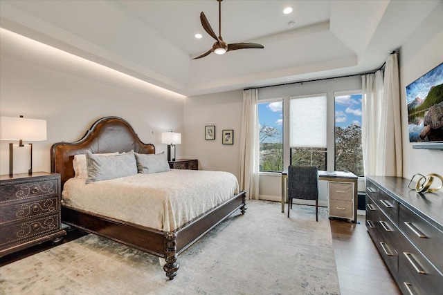 bedroom featuring a raised ceiling, wood finished floors, a ceiling fan, and recessed lighting