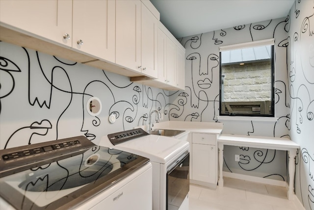 laundry area with washing machine and dryer, cabinet space, a sink, and light tile patterned floors