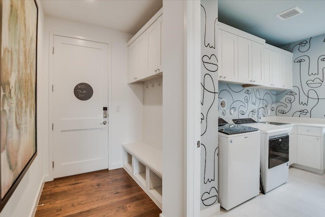 laundry area with cabinet space, visible vents, light wood-style floors, separate washer and dryer, and a sink