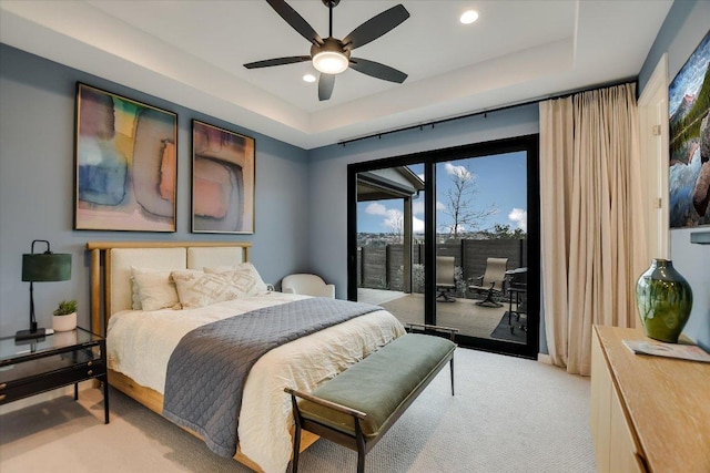 bedroom with access to exterior, a tray ceiling, light carpet, and recessed lighting