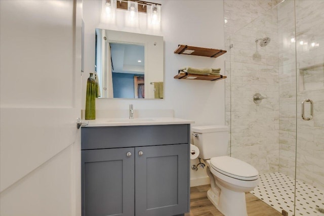 bathroom featuring vanity, a stall shower, wood finished floors, and toilet