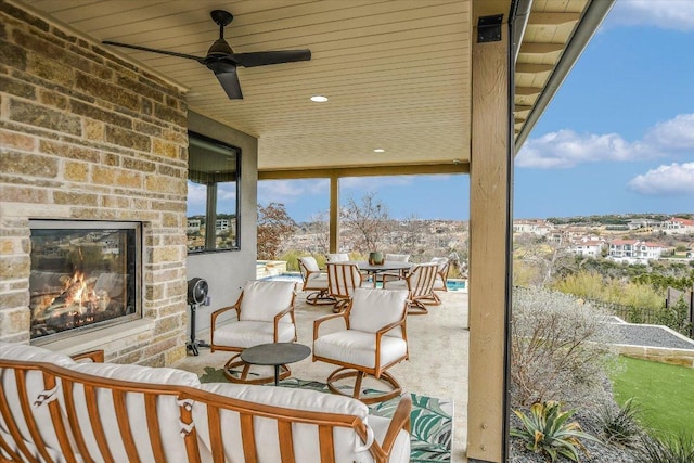 view of patio with ceiling fan and an outdoor stone fireplace