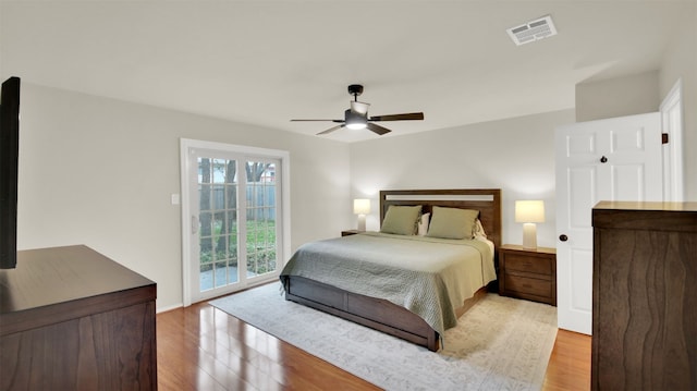 bedroom with access to outside, visible vents, ceiling fan, and wood finished floors