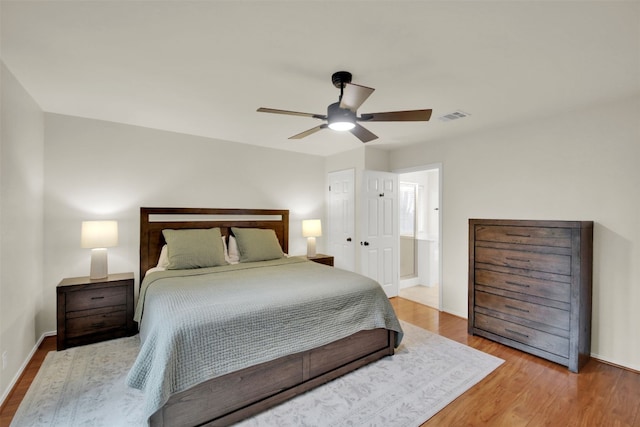 bedroom with a ceiling fan, baseboards, visible vents, and wood finished floors