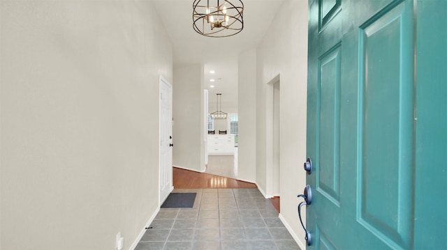 hallway featuring a chandelier, recessed lighting, baseboards, and tile patterned floors