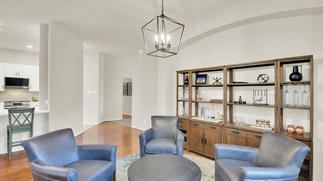 living area featuring light wood-style floors, lofted ceiling, baseboards, and an inviting chandelier