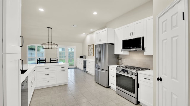 kitchen with decorative light fixtures, light countertops, backsplash, appliances with stainless steel finishes, and white cabinets