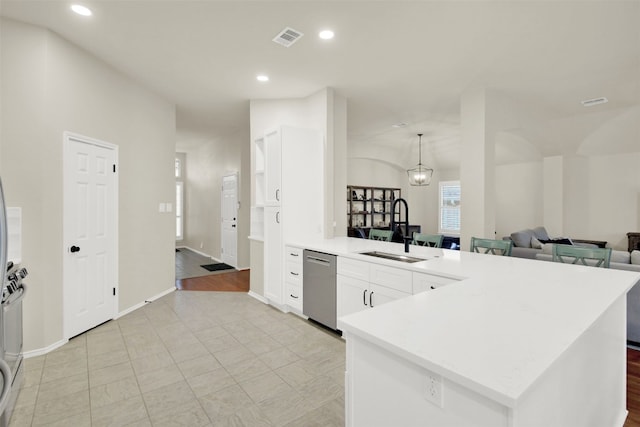 kitchen featuring visible vents, stainless steel dishwasher, white cabinetry, a sink, and a peninsula