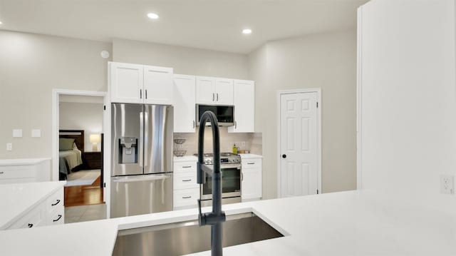 kitchen with recessed lighting, stainless steel appliances, white cabinetry, light countertops, and backsplash