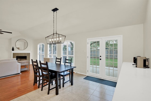 dining space featuring vaulted ceiling, french doors, a fireplace, and light tile patterned floors