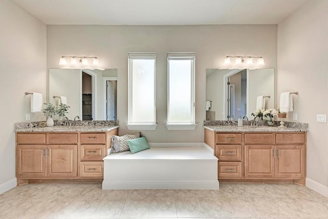 bathroom with two vanities, a sink, and baseboards