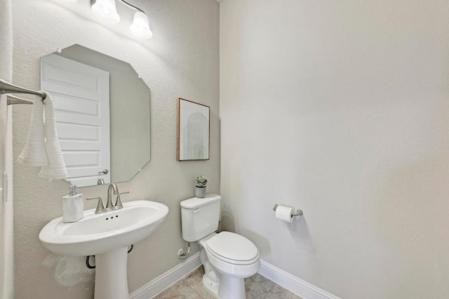 bathroom with tile patterned flooring, baseboards, and toilet