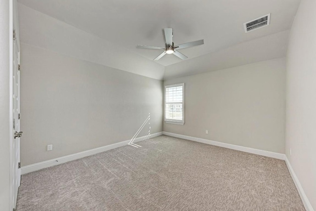 carpeted spare room with vaulted ceiling, visible vents, ceiling fan, and baseboards