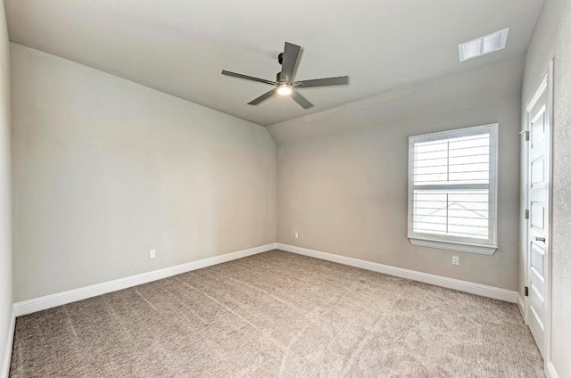 carpeted empty room with ceiling fan, vaulted ceiling, visible vents, and baseboards