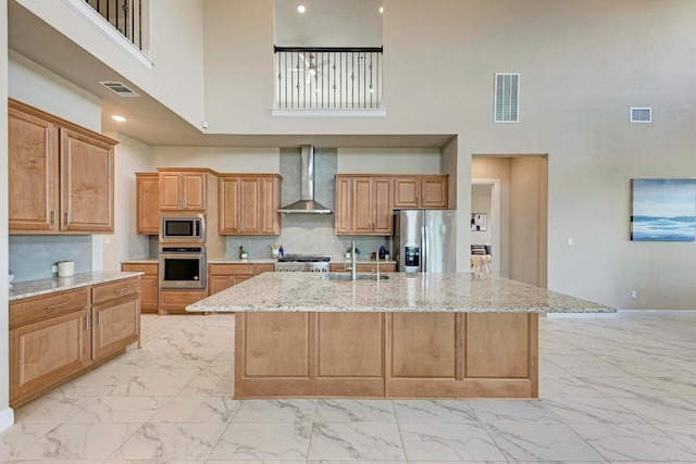 kitchen featuring marble finish floor, visible vents, appliances with stainless steel finishes, a sink, and wall chimney exhaust hood