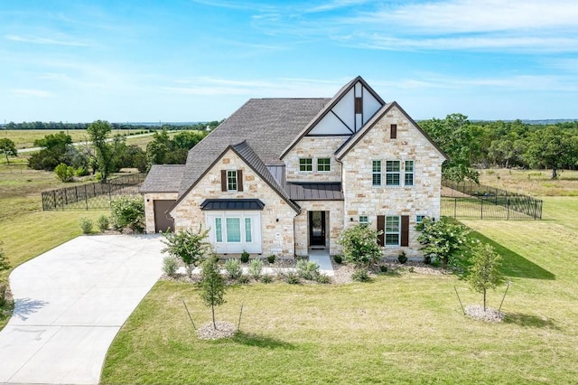 view of front of property featuring driveway, a standing seam roof, fence, and a front lawn