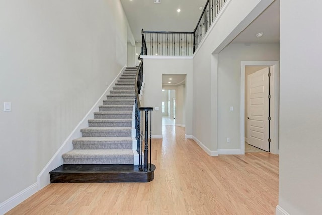 stairs featuring a high ceiling, baseboards, and wood finished floors