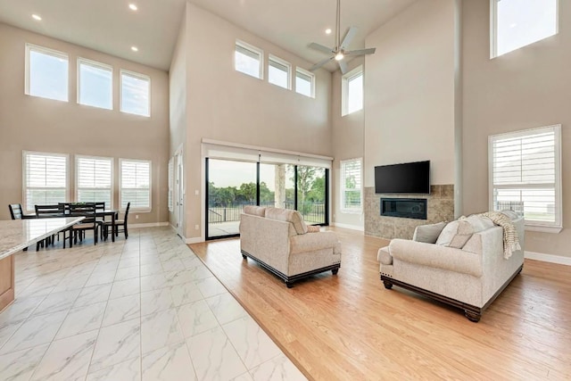 living room featuring a tile fireplace, marble finish floor, plenty of natural light, and baseboards