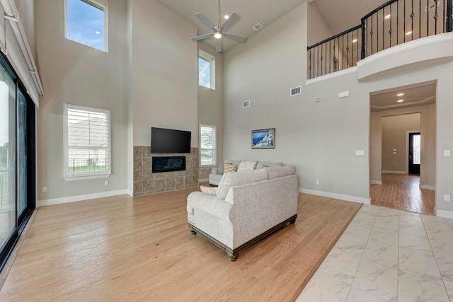 living area with plenty of natural light, visible vents, baseboards, and a tile fireplace