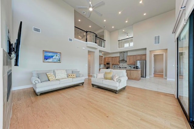 living room with light wood-style floors, visible vents, and a ceiling fan