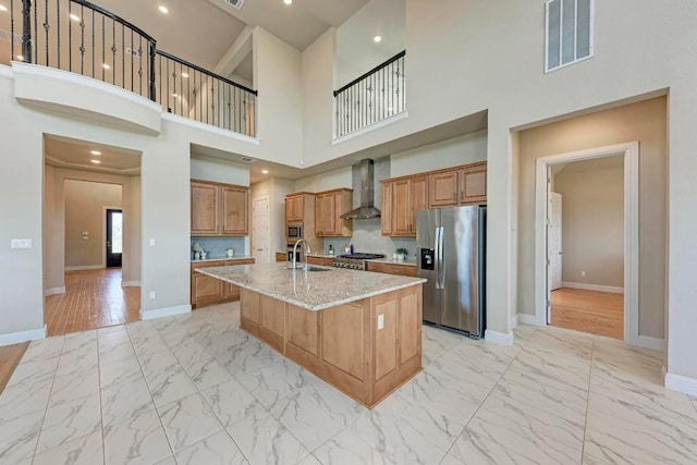 kitchen with marble finish floor, visible vents, appliances with stainless steel finishes, a kitchen island with sink, and wall chimney range hood