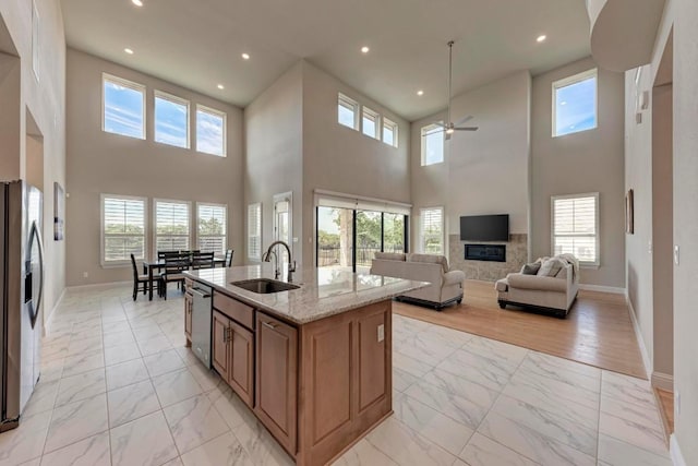 kitchen featuring stainless steel appliances, a sink, baseboards, marble finish floor, and light stone countertops