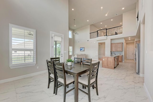 dining room featuring recessed lighting, marble finish floor, a high ceiling, and baseboards