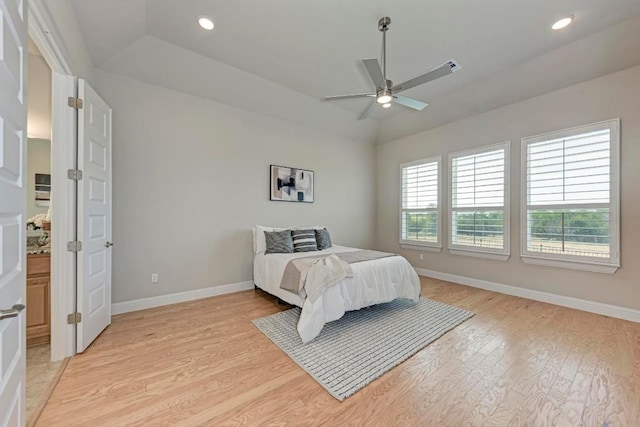 bedroom featuring baseboards, a tray ceiling, recessed lighting, and light wood-style floors