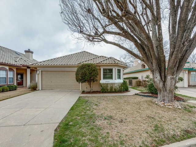 view of front of house with a garage, a tiled roof, concrete driveway, stucco siding, and a front yard