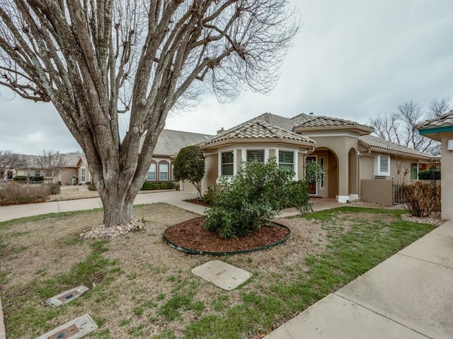 mediterranean / spanish house featuring a tiled roof, concrete driveway, and stucco siding