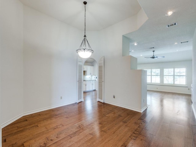 unfurnished dining area featuring a ceiling fan, baseboards, visible vents, and wood finished floors