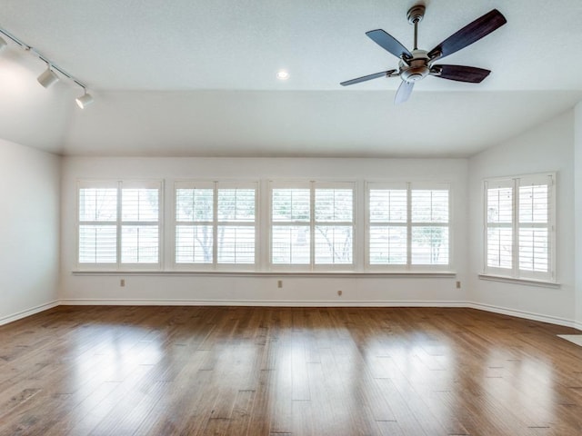 empty room featuring vaulted ceiling, wood finished floors, a ceiling fan, and baseboards