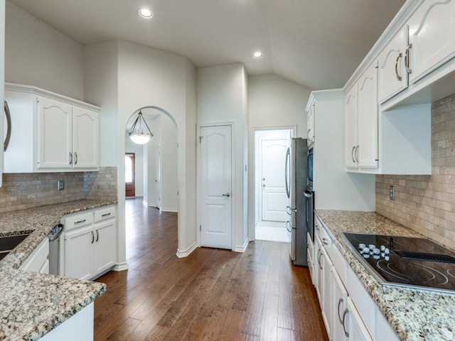 kitchen featuring arched walkways, black electric stovetop, dark wood-type flooring, and white cabinetry