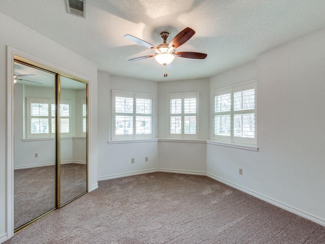 unfurnished bedroom with a textured ceiling, carpet flooring, visible vents, and baseboards