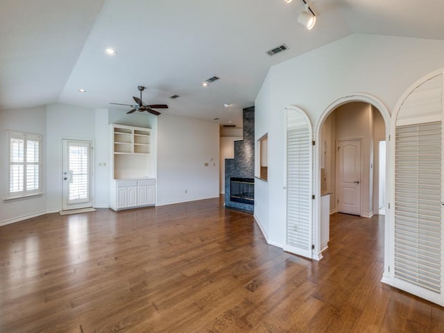 unfurnished living room featuring arched walkways, visible vents, a ceiling fan, wood finished floors, and a multi sided fireplace