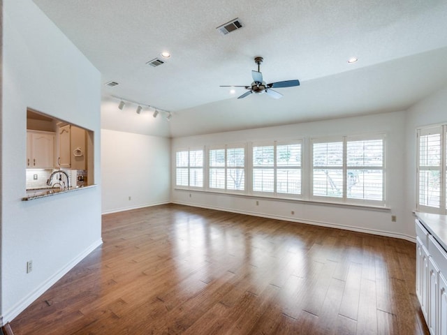 unfurnished living room with lofted ceiling, wood finished floors, visible vents, and baseboards