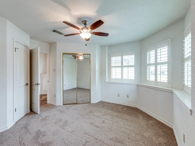 unfurnished bedroom featuring baseboards, visible vents, a ceiling fan, carpet, and a textured ceiling