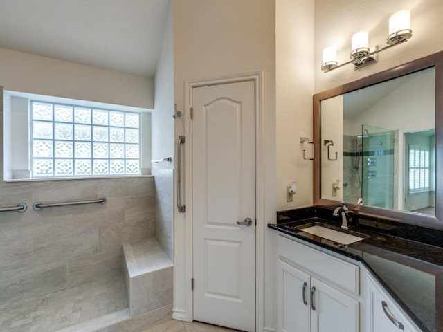 bathroom featuring vaulted ceiling, a stall shower, vanity, and a wealth of natural light