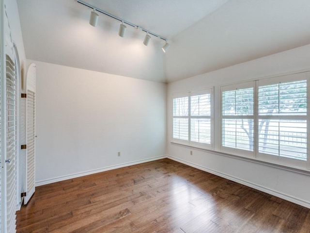 empty room with vaulted ceiling, wood finished floors, and baseboards