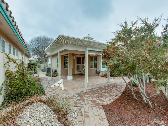 back of property with stucco siding, fence, a pergola, and a patio