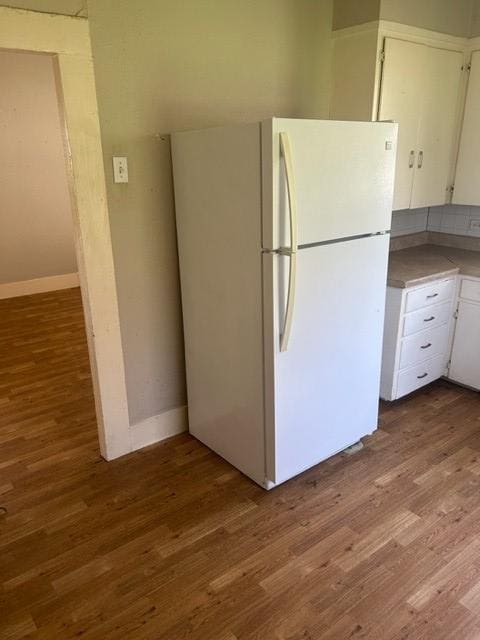 kitchen with white cabinetry, light countertops, wood finished floors, and freestanding refrigerator