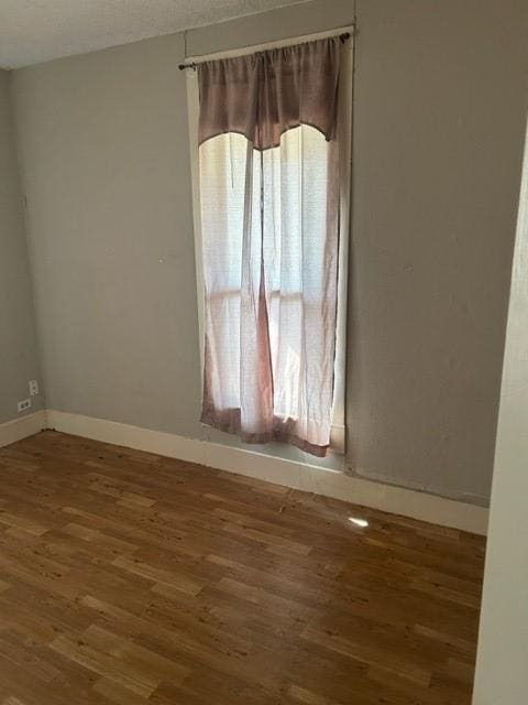 unfurnished room featuring baseboards and wood finished floors