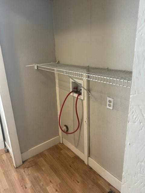 laundry room with washer hookup, baseboards, and wood finished floors