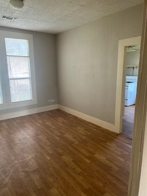 spare room with baseboards, a textured ceiling, visible vents, and wood finished floors