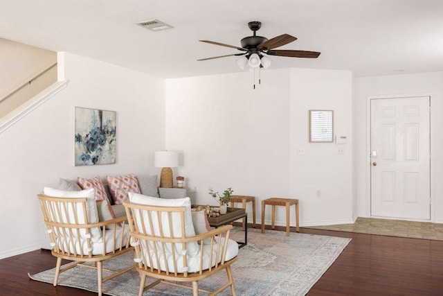 living area with a ceiling fan, visible vents, baseboards, and wood finished floors