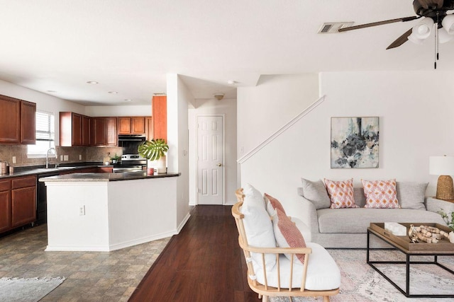 kitchen featuring dark countertops, ceiling fan, range hood, stainless steel range with electric stovetop, and backsplash