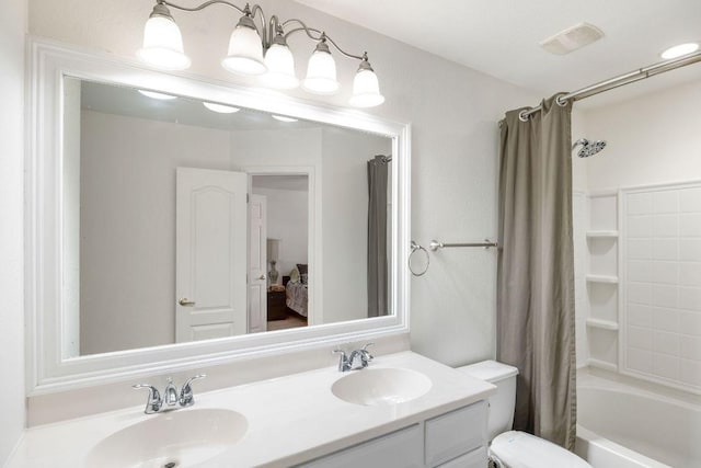 ensuite bathroom with toilet, double vanity, a sink, and visible vents