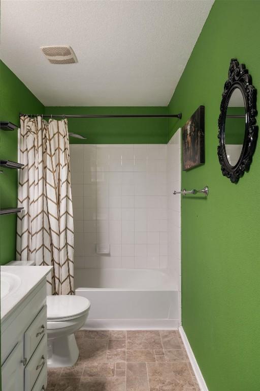 bathroom with visible vents, toilet, shower / bath combo, vanity, and baseboards