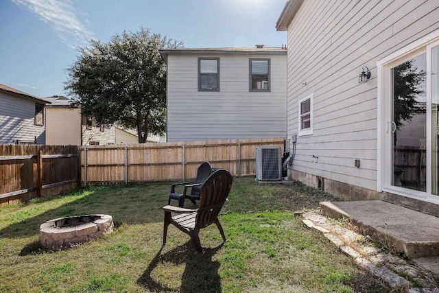 view of yard featuring a fire pit, central AC unit, and a fenced backyard